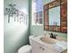 Small powder room with a pedestal sink and decorative mirror at 9420 Old Hyde Park Pl, Lakewood Ranch, FL 34202