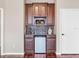 Home wet bar with wood cabinets, a mini-fridge, and tile backsplash at 9420 Old Hyde Park Pl, Lakewood Ranch, FL 34202