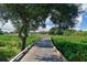 Wooden boardwalk path leads to a home with lush green landscape at 9818 Discovery Ter, Bradenton, FL 34212