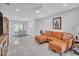 Bright living room with orange sectional sofa and polished concrete floors at 120 Edgewater Ter, Dunedin, FL 34698