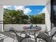 Relaxing balcony features a table and chairs with a view of lush trees at 1255 N Gulfstream Ave # 204, Sarasota, FL 34236
