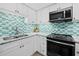 Modern kitchen with stainless steel appliances and a teal and white hexagon tile backsplash at 1255 N Gulfstream Ave # 204, Sarasota, FL 34236