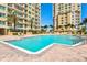 Large, sparkling swimming pool surrounded by resort buildings, palm trees and comfortable lounge chairs at 130 Riviera Dunes Way # 1104, Palmetto, FL 34221