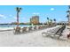 Picturesque view of lounge chairs on sandy area near a community pool and a high rise condo building with palm trees at 130 Riviera Dunes Way # 1104, Palmetto, FL 34221