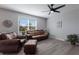 Living room with brown leather furniture, ceiling fan, and large window at 15404 Trinity Fall Way, Bradenton, FL 34212