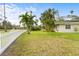 Landscaped front yard with lush lawn, palm trees, and white picket fence at 4810 Bay Shore Rd, Sarasota, FL 34234