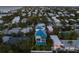 Aerial view of a modern home with a private pool and a lush green lawn, close to the ocean at 518 Spring Ave, Anna Maria, FL 34216