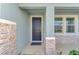 House entrance with dark gray door, stone accents, and two windows at 5755 Woodland Sage Dr, Sarasota, FL 34238