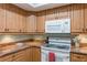 View of kitchen with wood cabinets and white appliances at 610 Estuary Dr # 610, Bradenton, FL 34209