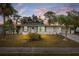 White single story home with palm trees and a landscaped yard at dusk at 8142 Coco Solo Ave, North Port, FL 34287