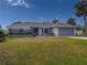 House exterior with gray garage door and lush landscaping at 9008 Allapata Ln, Venice, FL 34293
