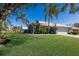 Single story house with a lush lawn, palm trees, and a large oak tree at 7203 41St E Ct, Sarasota, FL 34243