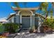 Charming house entrance with a teal door, arched entryway, and lush landscaping at 7203 41St E Ct, Sarasota, FL 34243