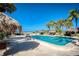 Community pool with lounge chairs and thatch umbrellas at 1212 Benjamin Franklin Dr # 305, Sarasota, FL 34236