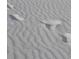 Close-up view of beach sand with wave patterns and footprints at 1260 Dolphin Bay Way # 303, Sarasota, FL 34242