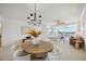 Bright dining room with a round wooden table and white chairs, overlooking the living room and balcony at 1280 Dolphin Bay Way # 202, Sarasota, FL 34242