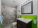 Modern bathroom with a glass shower, dark vanity, and green wainscoting at 1981 Bayshore Dr, Englewood, FL 34223