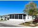 White mobile home with screened porch, paved patio, and landscaping at 3411 Spanish Oak Ter, Sarasota, FL 34237