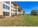 Manicured condo lawn with a glimpse of the waterfront and clear blue skies at 3810 Gulf Of Mexico Dr # F105, Longboat Key, FL 34228