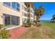 Exterior shot of the condo, featuring a brick patio, expansive lawn, and partial water views at 3810 Gulf Of Mexico Dr # F105, Longboat Key, FL 34228