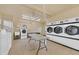 Bright laundry room with multiple high-efficiency washers and dryers, folding table, utility sink at 3810 Gulf Of Mexico Dr # F105, Longboat Key, FL 34228