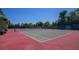 Two red tennis courts with nets and benches, surrounded by trees at 401 Spring Lakes Blvd # 401, Bradenton, FL 34210