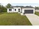 A modern, single-story home with a two-car garage and landscaped lawn at 5595 Delight Ave, North Port, FL 34288