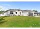 White house with gray roof and dark gray garage door, nicely landscaped lawn at 5595 Delight Ave, North Port, FL 34288