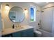 Modern bathroom with teal vanity, a large mirror, and a tub at 630 Companion Way, Longboat Key, FL 34228