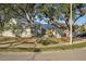 Exterior view of a light green house with a metal roof, landscaping, and a large tree at 510 45Th E St, Bradenton, FL 34208