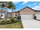 Front view of a tan house with a white garage door and palm trees at 5914 Fiore Dr, Bradenton, FL 34208