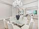 Open concept dining room with glass table, chandelier, and living room view at 7917 Mainsail Ln, Sarasota, FL 34240