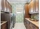 Bright laundry room with shaker cabinets, granite countertops and tropical wallpaper at 8253 Grande Shores Dr, Sarasota, FL 34240