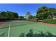 Outdoor tennis court with green and red surface, surrounded by mature trees and hedges at 850 S Tamiami Trl # 408, Sarasota, FL 34236