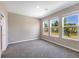 Bedroom with three windows, gray carpet, and access to bathroom at 15093 Shady Palms Ln, Nokomis, FL 34275