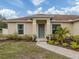 Front view of a tan house with a gray door and landscaping at 4352 Adelaide Ave, North Port, FL 34288