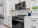 Modern kitchen with white cabinets, stainless steel appliances, and tile backsplash at 5940 Driftwood Ave # 15, Sarasota, FL 34231