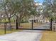 Entrance with black metal gate and wood fencing at 8107 High Oaks Trl, Myakka City, FL 34251