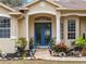 Front porch with blue door and rocking chairs at 8107 High Oaks Trl, Myakka City, FL 34251