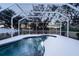 Screened pool at dusk, surrounded by lush trees at 1178 Fraser Pine Blvd, Sarasota, FL 34240