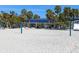 Beach view showing a volleyball net, palm trees, and a blue beach access roof at 1906 Harbour Links Cir # 14, Longboat Key, FL 34228