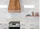Modern kitchen with wood range hood and white cabinets at 1906 Harbour Links Cir # 14, Longboat Key, FL 34228