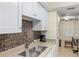 Modern kitchen with white cabinets, double sink, and mosaic backsplash at 204 3Rd W St # 203, Bradenton, FL 34205