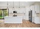 Bright kitchen featuring white cabinets, a large island, and wood-look flooring at 4497 N Salford Blvd, North Port, FL 34286