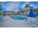 Community pool with patio furniture and umbrellas at 5469 Fair Oaks Street St # 5C, Bradenton, FL 34203