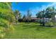 Green grassy backyard with palm trees and a home in the background at 6739 Haverhill Ct, Lakewood Ranch, FL 34202