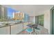 Condo balcony with a table set, offering a scenic view of palm trees, the tennis court, and nearby high-rise buildings at 1111 N Gulfstream Ave # 4E, Sarasota, FL 34236