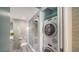 Clean bathroom with glass door shower, toilet and stacked washer and dryer in alcove at 1111 N Gulfstream Ave # 4E, Sarasota, FL 34236