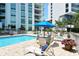 Community pool with patio furniture and a blue umbrella for shade at 1111 N Gulfstream Ave # 4E, Sarasota, FL 34236