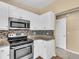 Bright kitchen featuring stainless steel appliances, a mosaic backsplash and white cabinets at 1382 Ronald St, North Port, FL 34286